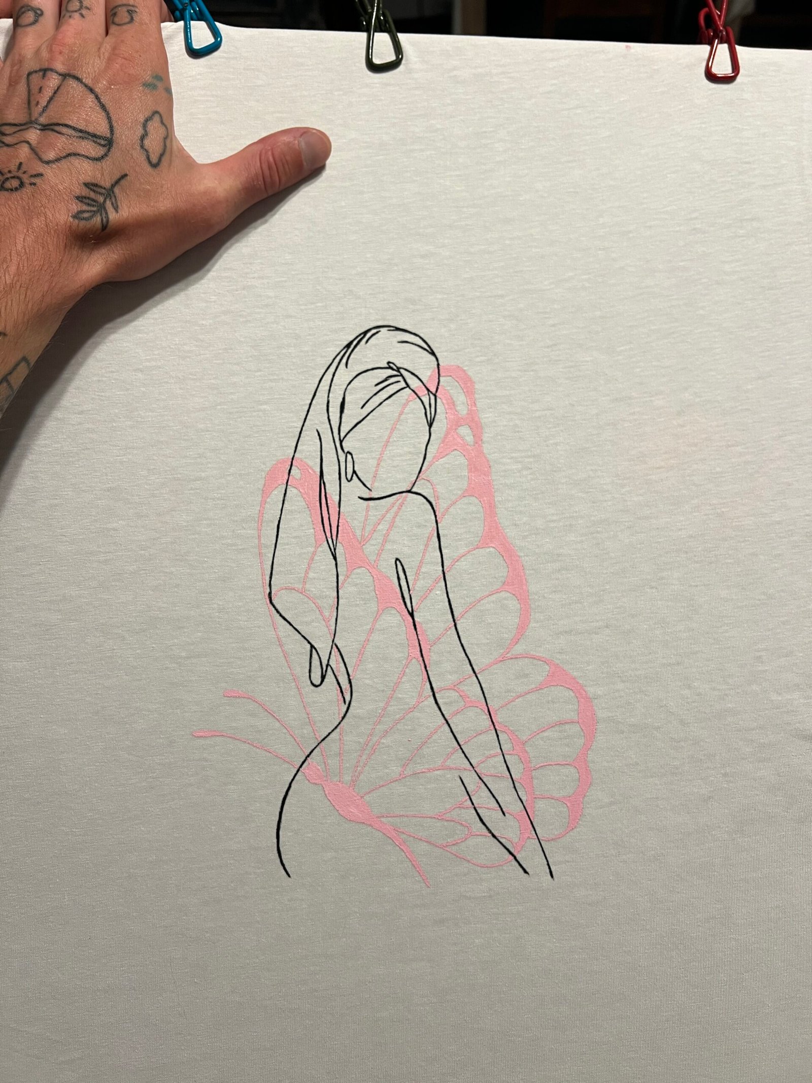 A hand and a drawing in a sketchbook