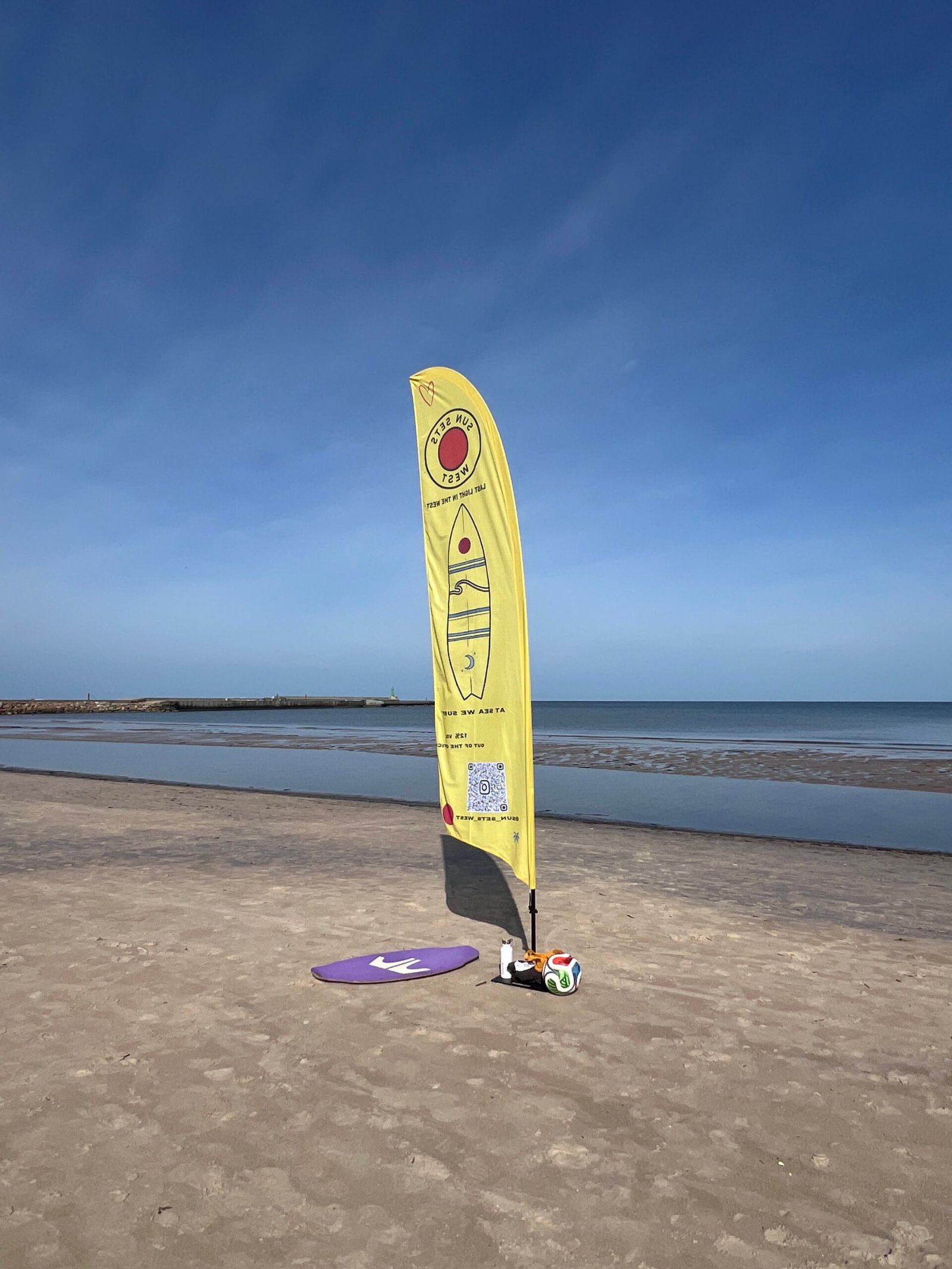 A yellow Sun Sets West flag on the beach beside the Baltic Sea