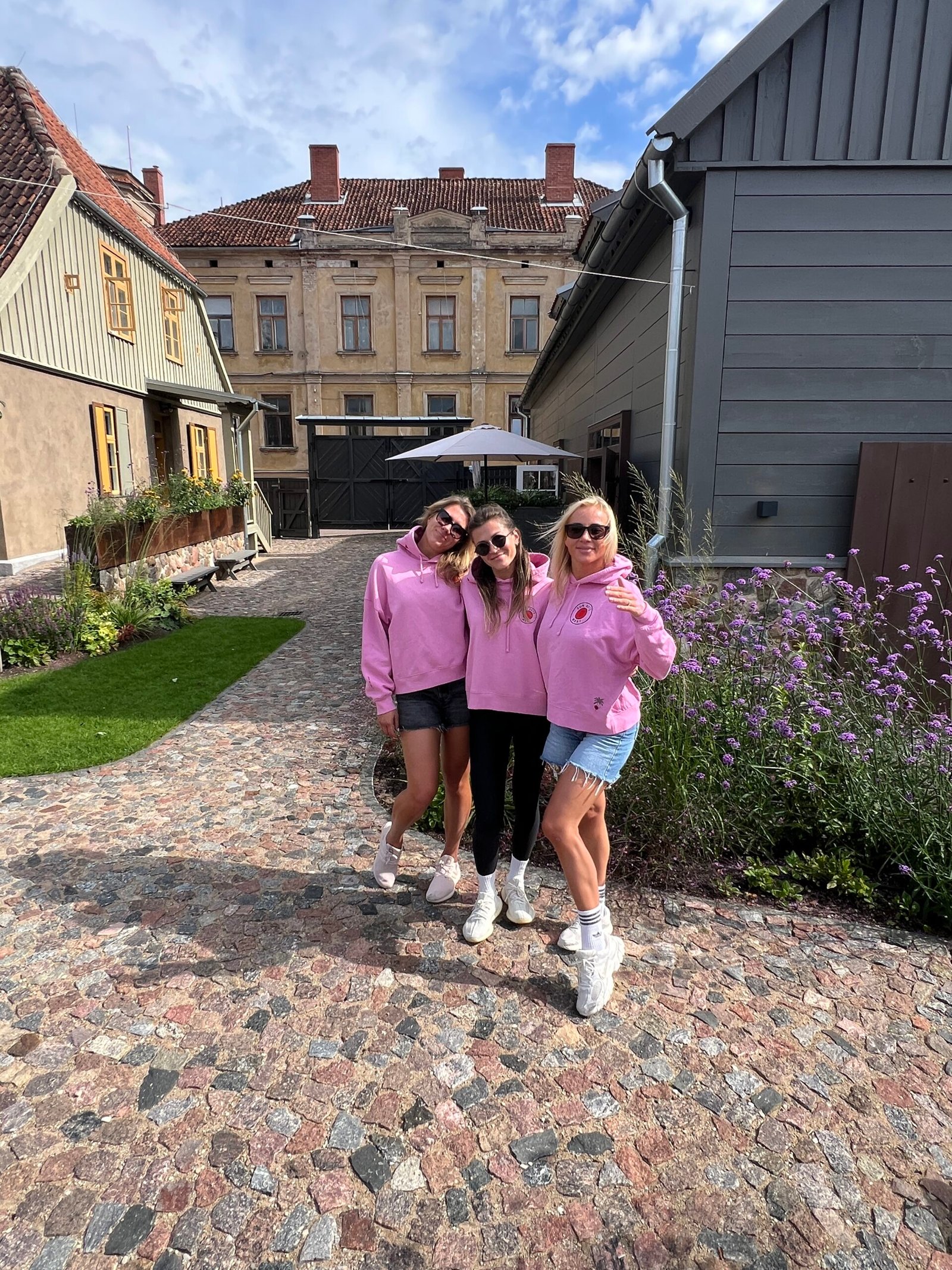 Friends wearing pink Sun Sets West hoodies outside